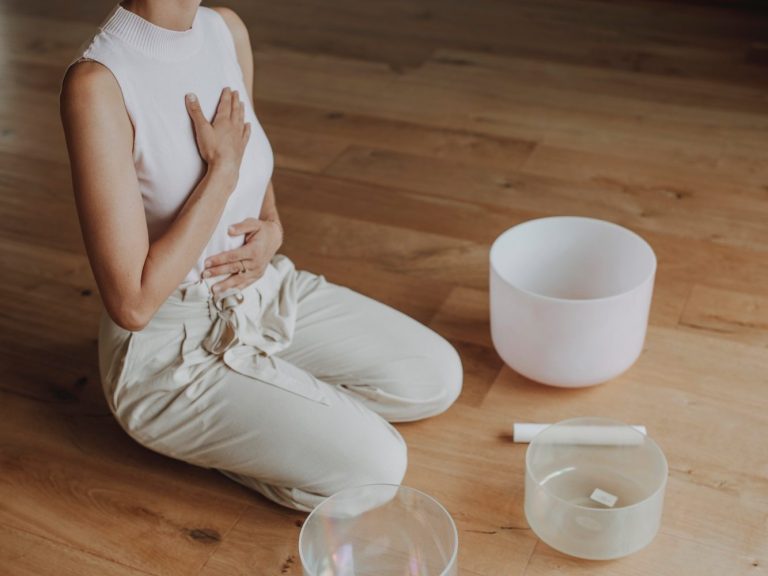 Meditation und Atemübungen Junge Frau in beige hält ihre Hände auf Bauch und Brustkorb und meditiert